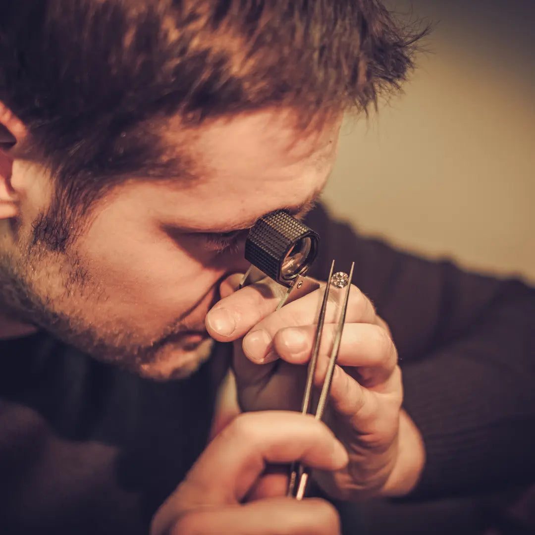 Mael gems, expert gemmologue analysant une pierre précieuse avec une loupe dans un atelier professionnel