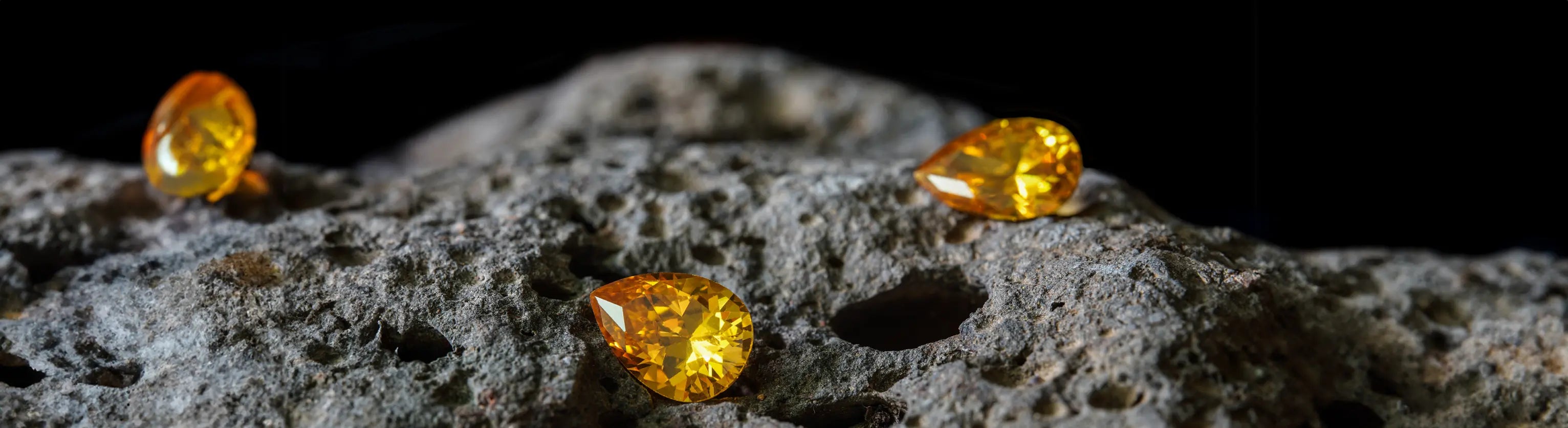 Trois saphirs jaunes taillés en forme de poire, disposés sur une pierre brute. Ces gemmes précieuses aux reflets dorés illustrent l'éclat et la pureté des pierres naturelles, idéales pour la joaillerie fine et les créations sur mesure. La taille experte de ces saphirs permet de sublimer leur jeu de lumière, mettant en valeur leur intensité et leur rareté.