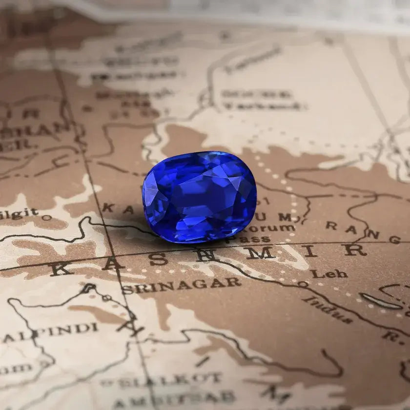 Saphir taillé d’un bleu profond, posé sur une carte ancienne, symbolisant le raffinement et l’expertise du travail lapidaire. La taille des pierres précieuses comme le saphir, le rubis, l’émeraude et la tourmaline est une étape essentielle en haute joaillerie, révélant leur éclat et leur pureté. Chaque facette est sculptée avec précision pour maximiser la réflexion de la lumière et sublimer la gemme. Mael Gems precious stones