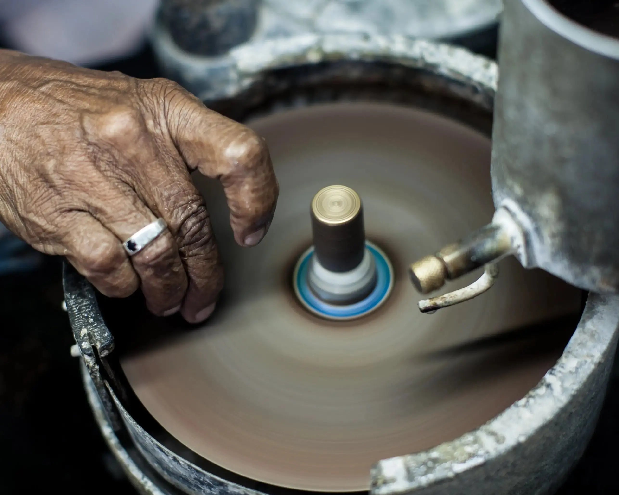 Main d’un artisan lapidaire taillant une pierre précieuse à la main sur une meule rotative traditionnelle dans un atelier.
Taille manuelle d’une pierre précieuse par un artisan lapidaire expérimenté.