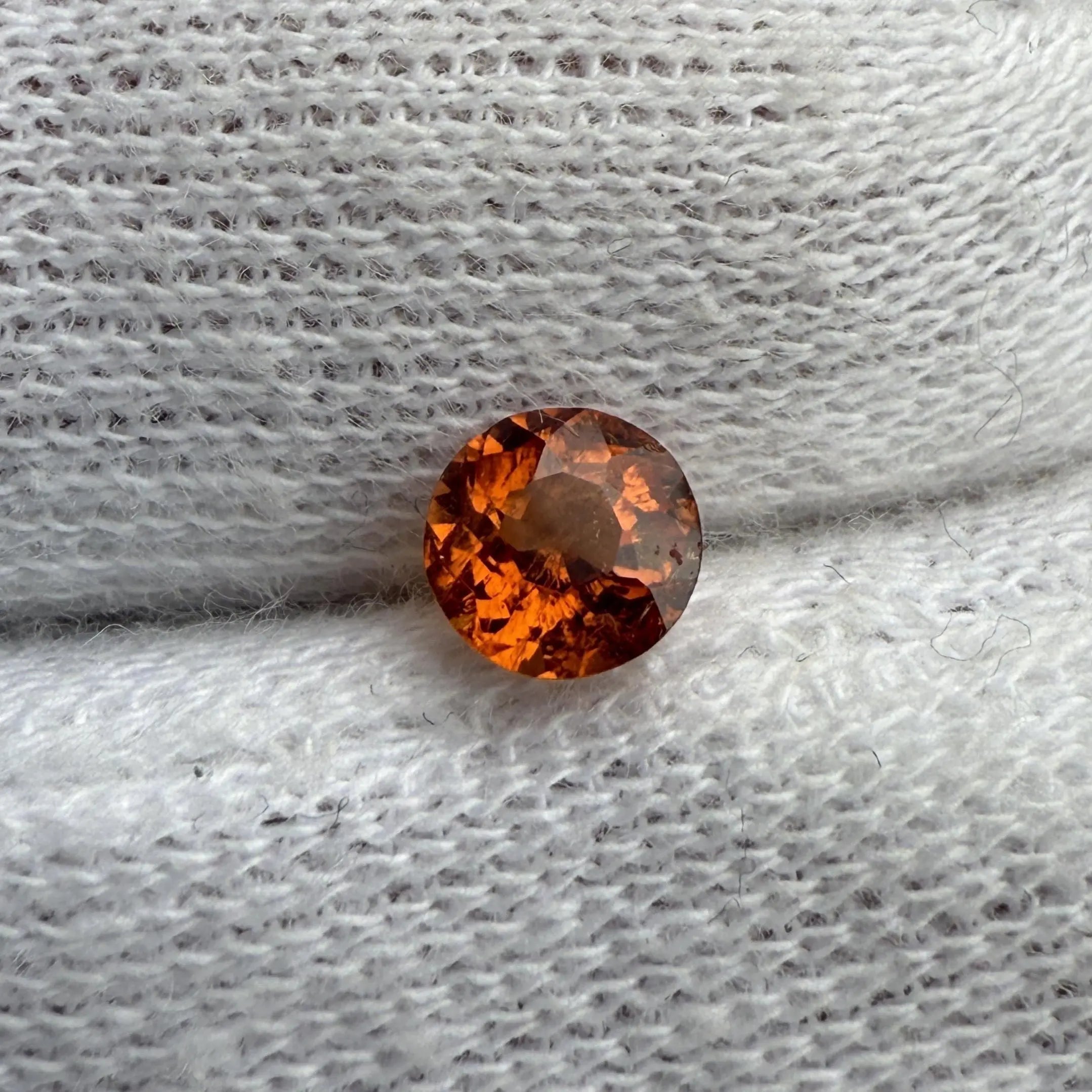 Gemme spessartite naturelle posée sur textile, 1.01 ct. Brillance exceptionnelle et teinte intense. une pierre précieuse intense qui offre un éclat digne du soleil levant. 